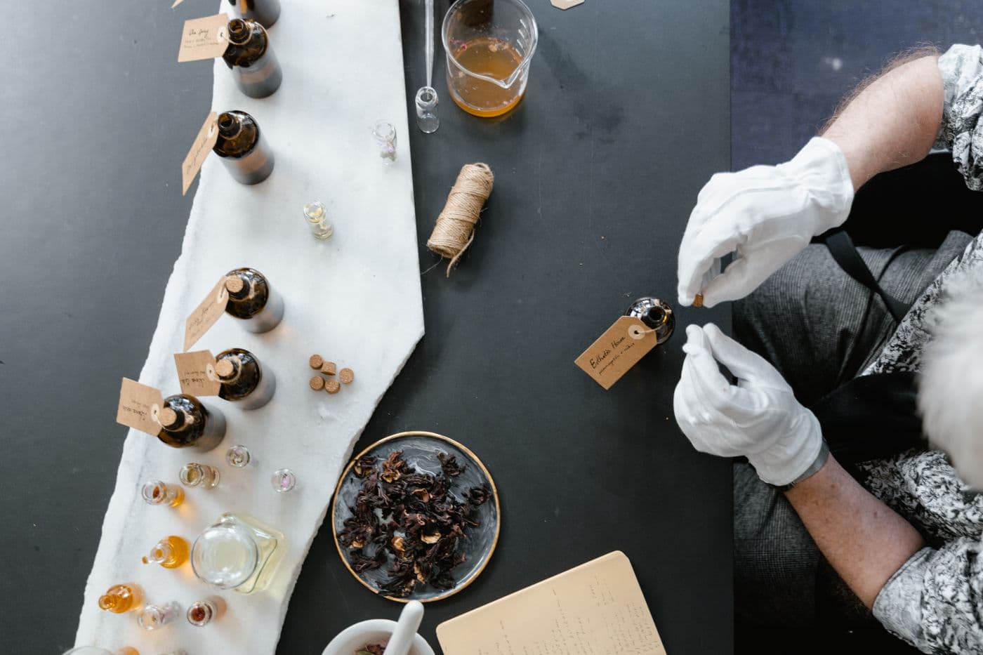 Fragrance oils and botanical ingredients being blended at a perfumery workbench
